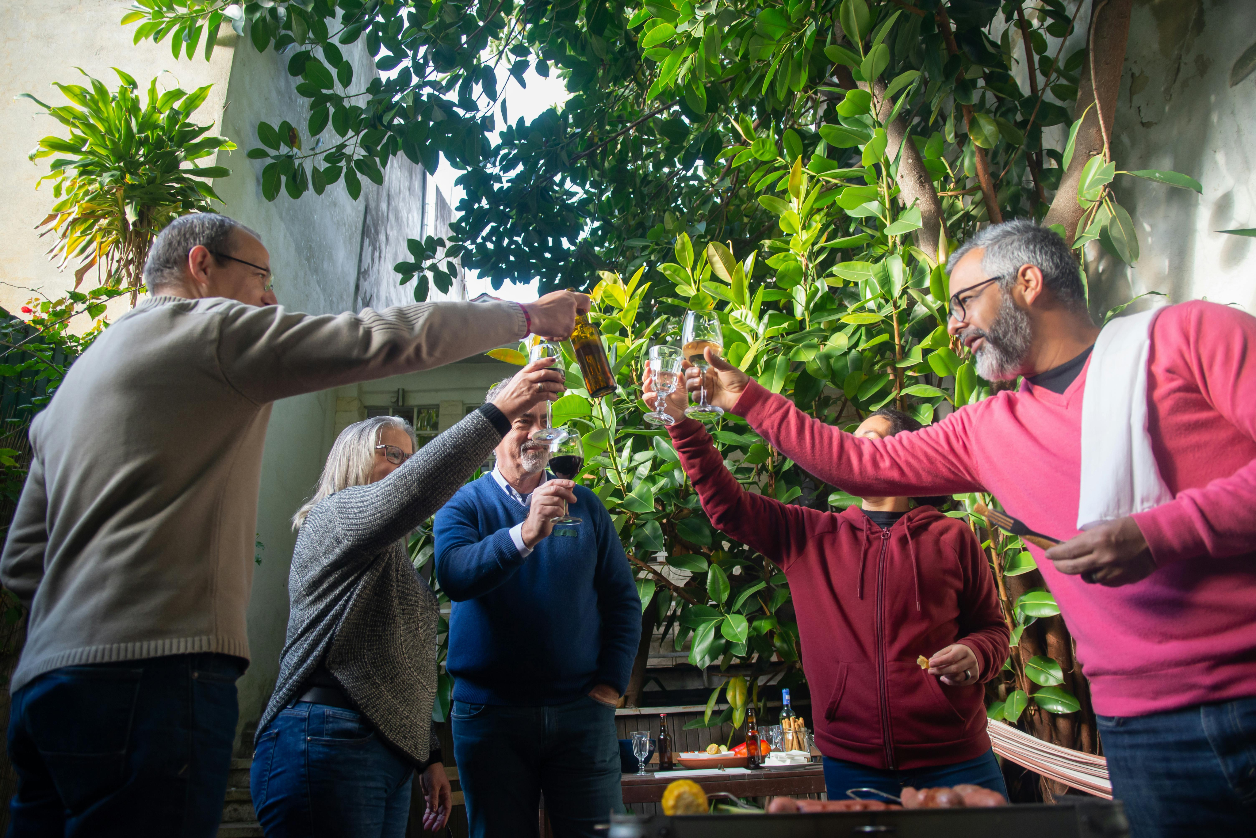Family and friends toasting with wine in a sunlit garden